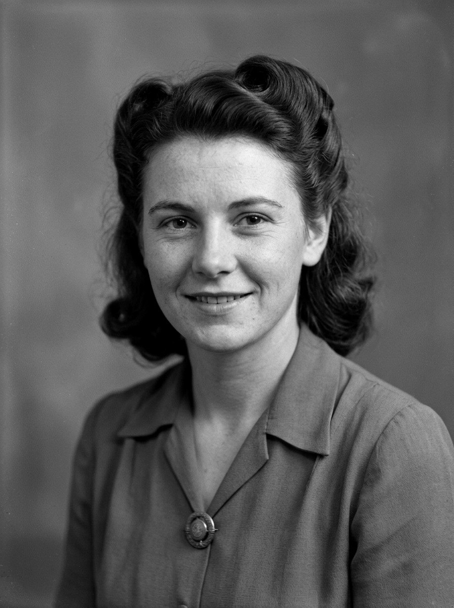 The same 1940s portrait restored in black and white: young woman in a collared blouse and brooch, softly smiling