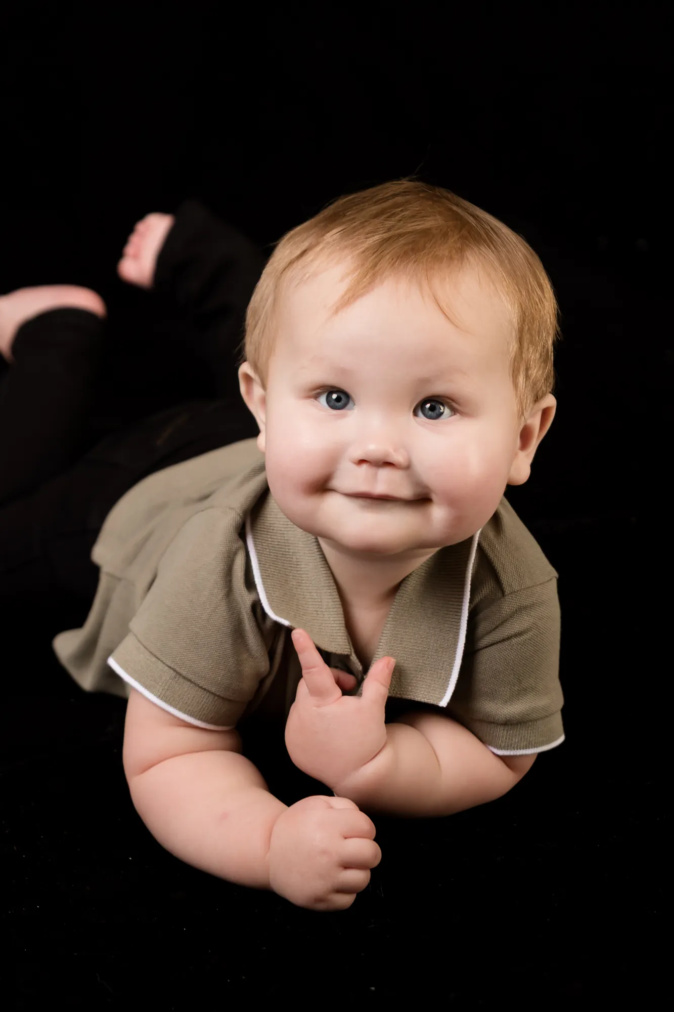 Baby boy lifting his head and smiling during tummy time at a sitter session